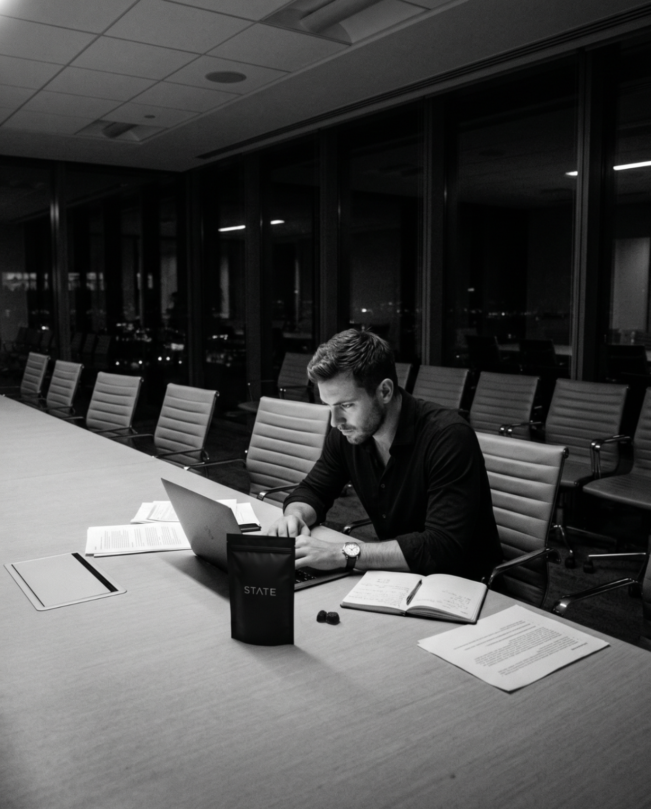 Founder working late at an empty boardroom table with a STATE pouch